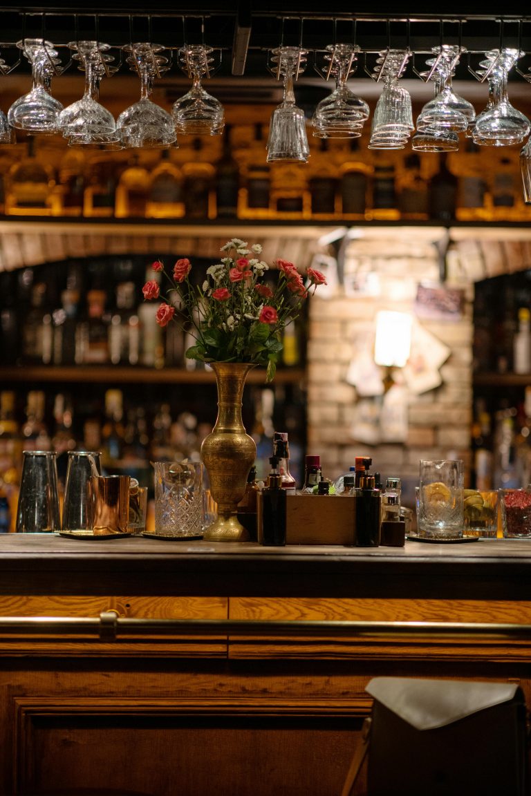 Notre cave Warm and inviting bar interior with hanging glasses, liquor bottles, and a floral arrangement on the counter.